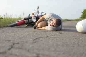 man holding his knee on the road after a motorcycle accident