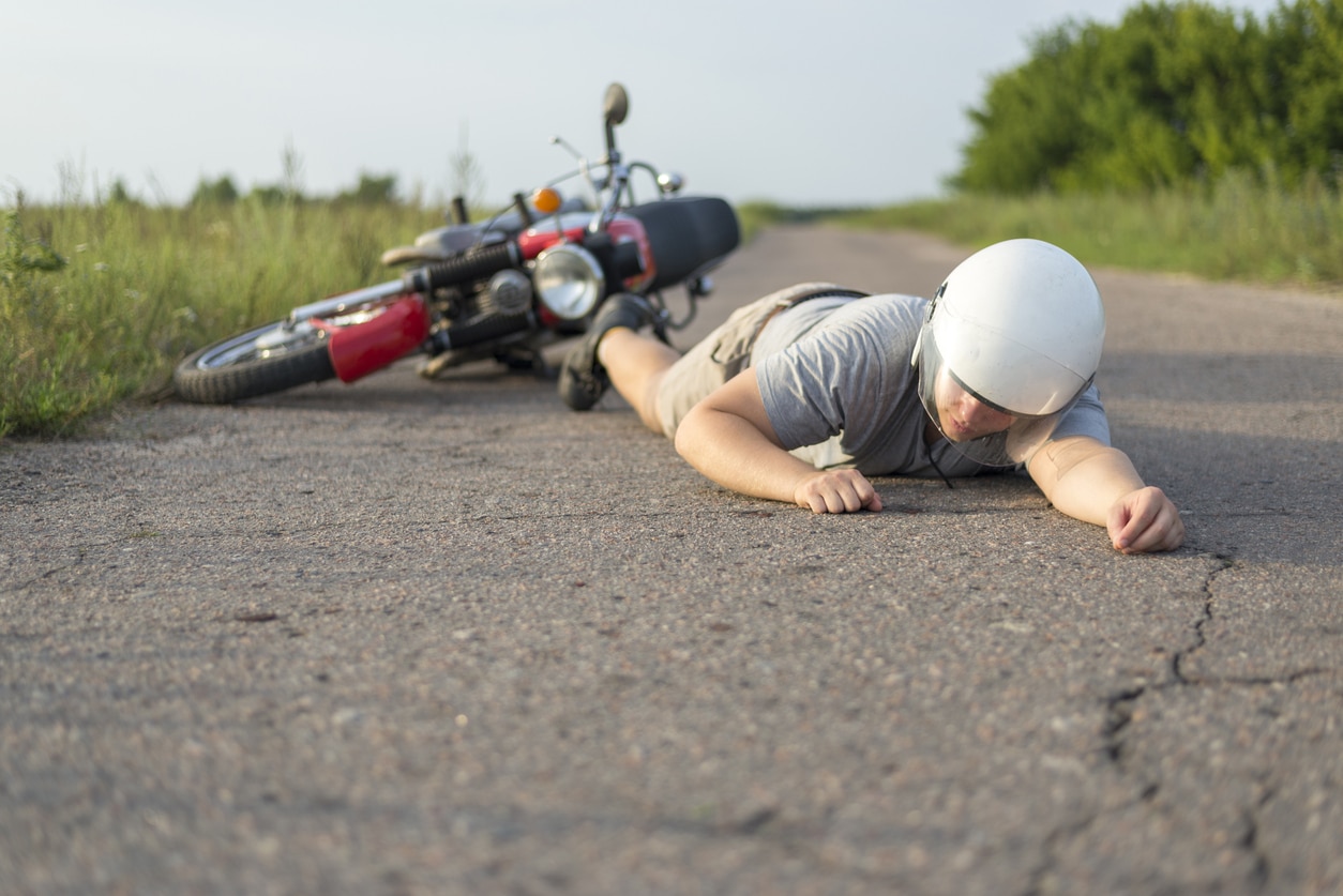 man lying on the road after a motorcycle accident