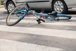 bicycle on the ground in a crosswalk after a collision with a car