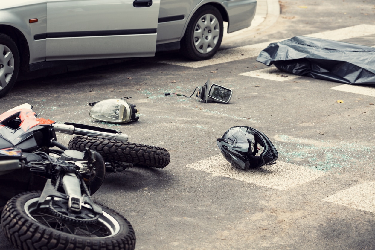 Black helmet and motorcycle on the road after motorcycle accident with a car